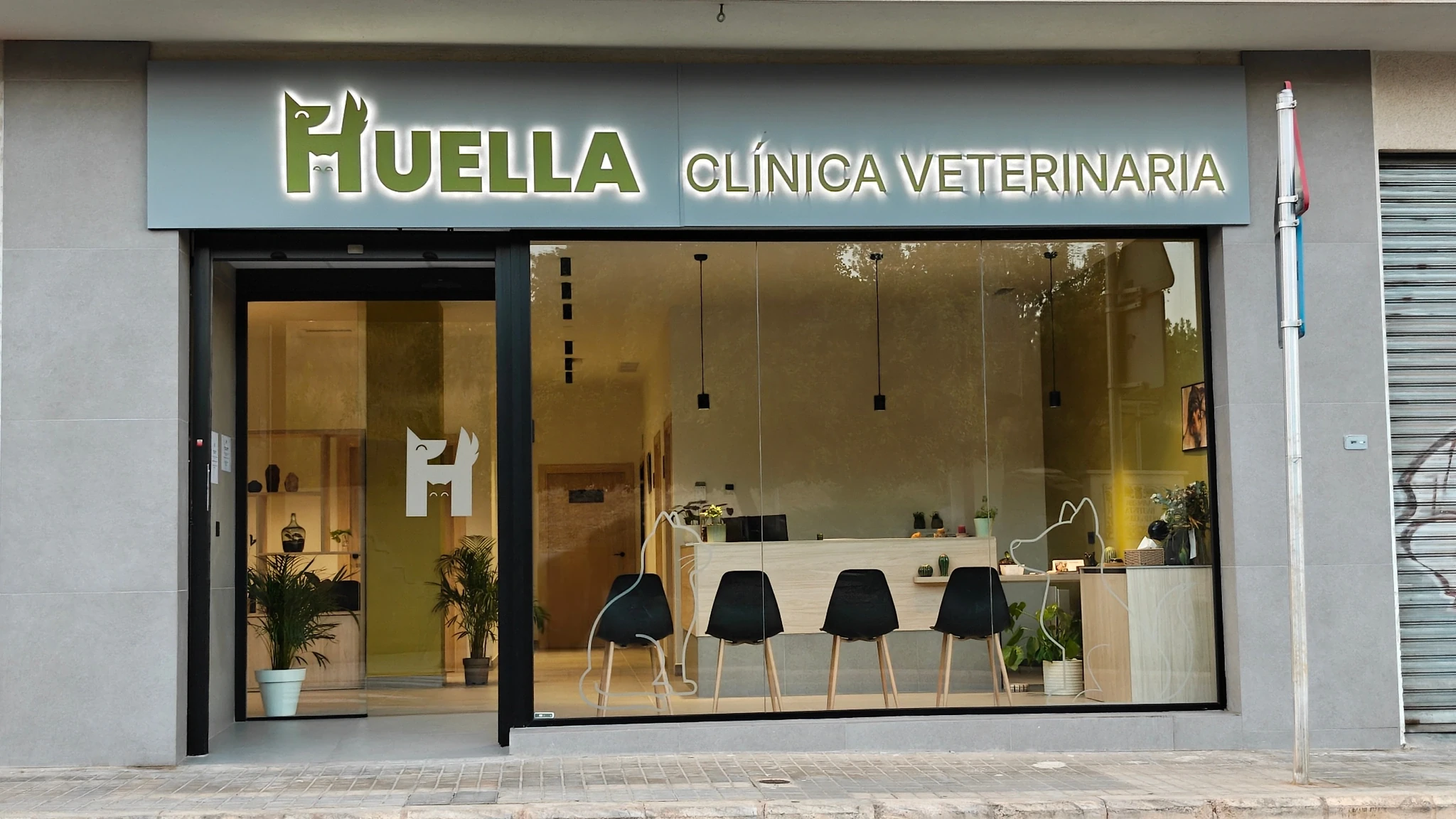 Fachada de la clínica veterinaria HUELLA en Turís, con el rótulo iluminado y el escaparate